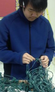 A WWG student working on the holiday lights they collected for recycling.