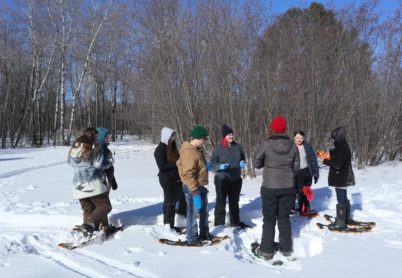 Group of students on snowshoes listening to instructor
