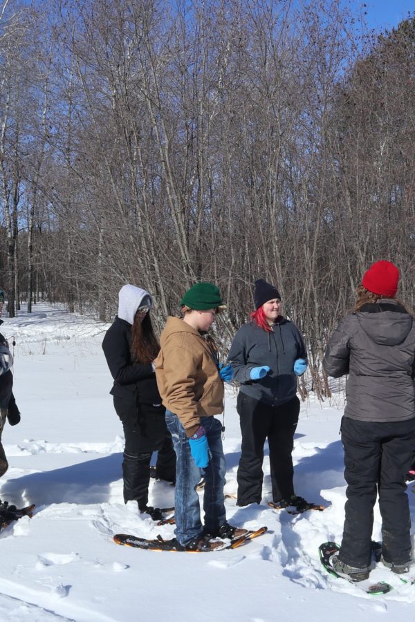 Group of students on snowshoes listening to instructor
